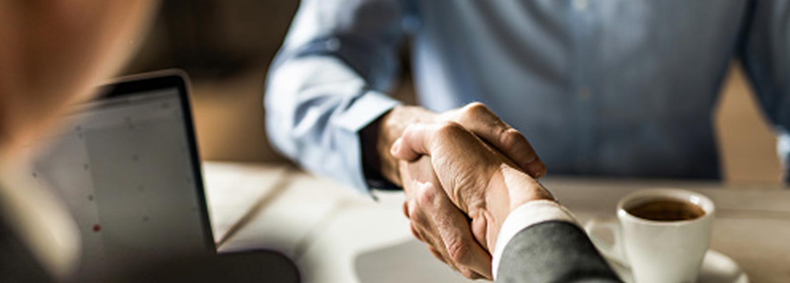 business handshake with tablet in background