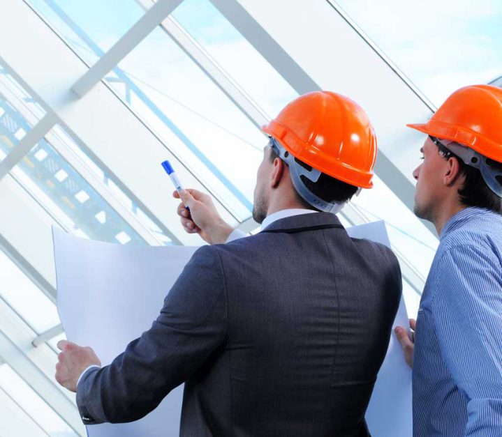 Construction professionals with hard hats reviewing plans